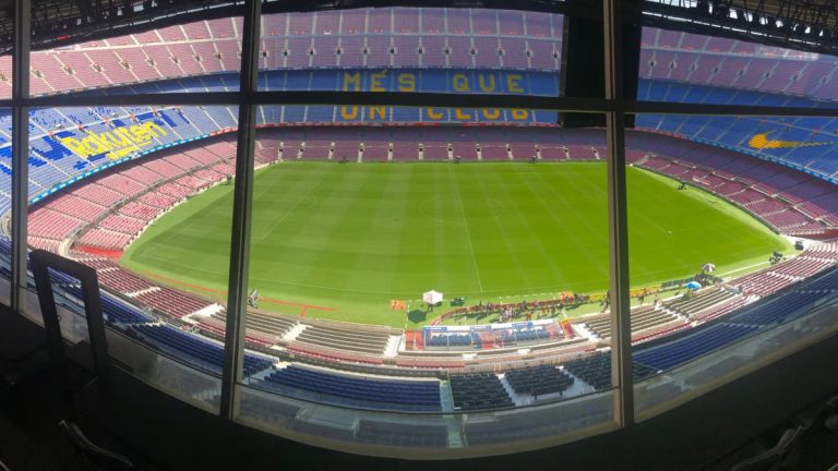Wide view of Camp Nou stadium showcasing its vast seating and green pitch.