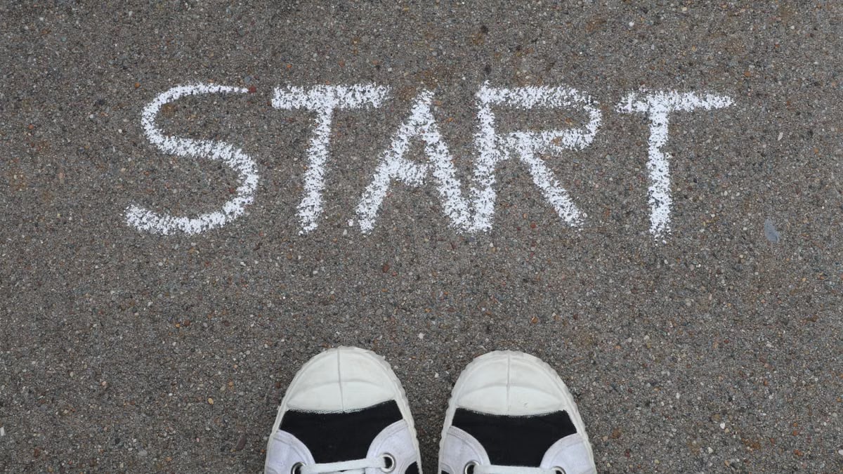 Close-up of sneakers and a 'START' chalk drawing on pavement, symbolizing new beginnings.